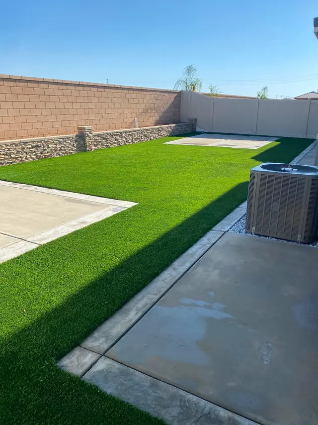 Artificial grass back yard against a block wall in Perris, CA