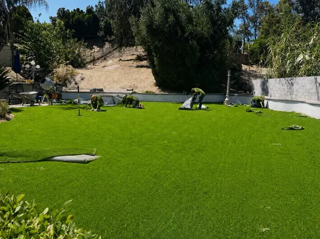 Millenium crew laying artificial turf across a large yard in Perris, CA