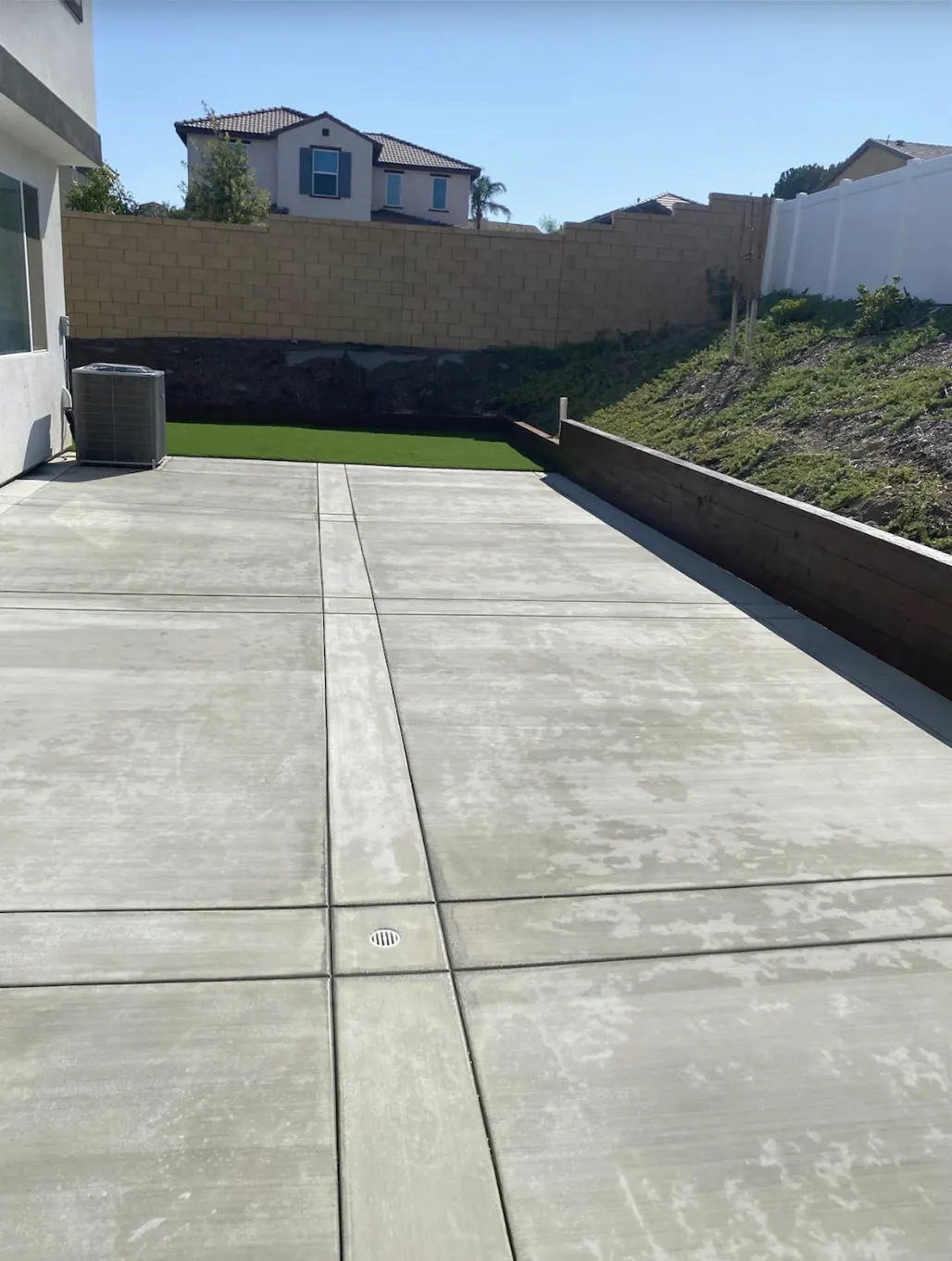 Full back yard with patio slab, block wall and turf